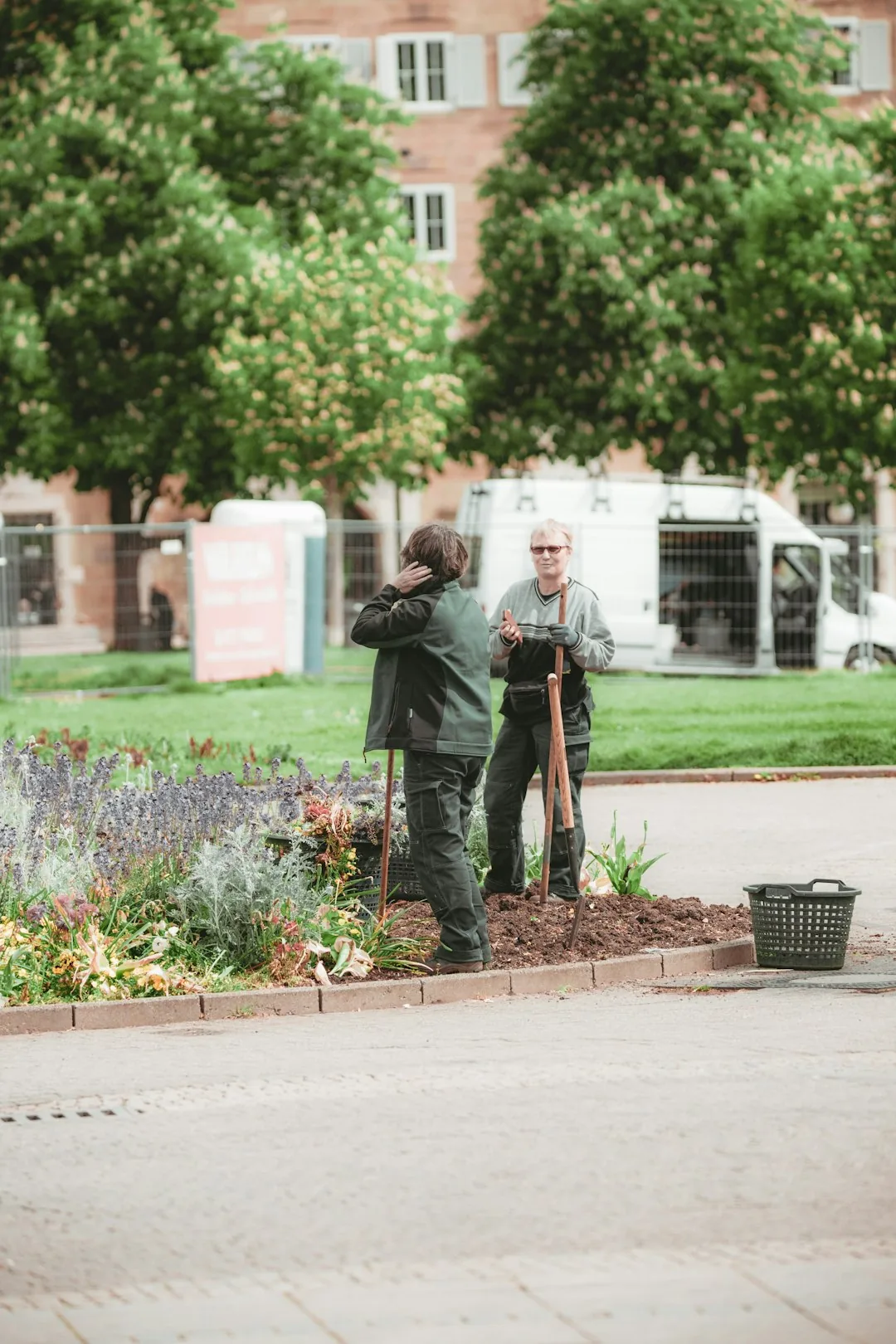Two SilverRainGrove gardeners pruning a young plum tree beside a slim rainwater tank